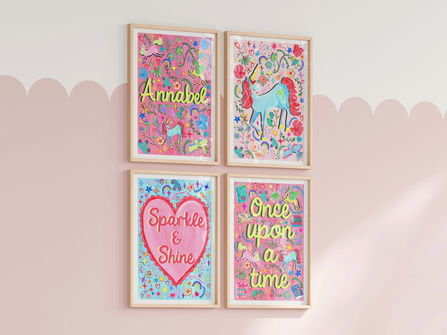 Four colorful framed prints with motivational phrases on a light pink wall.