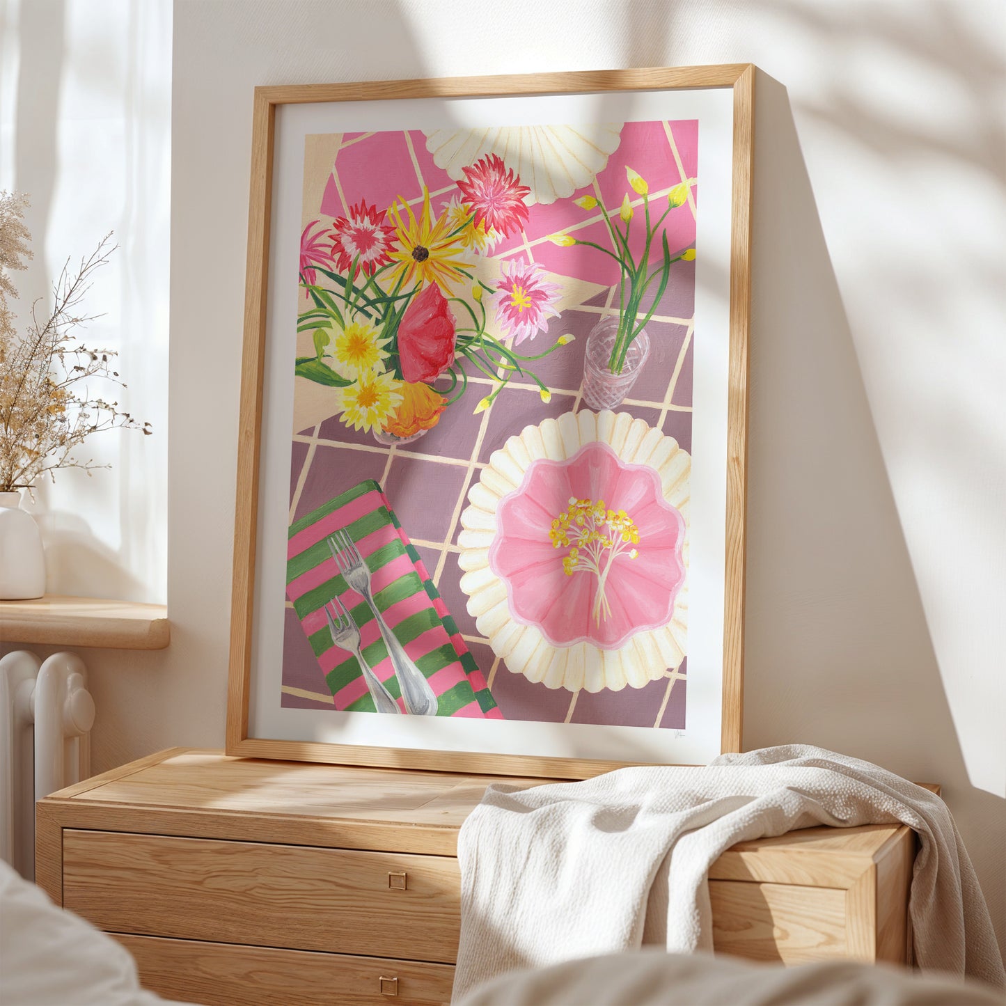 Framed floral artwork on a wall above a wooden dresser.