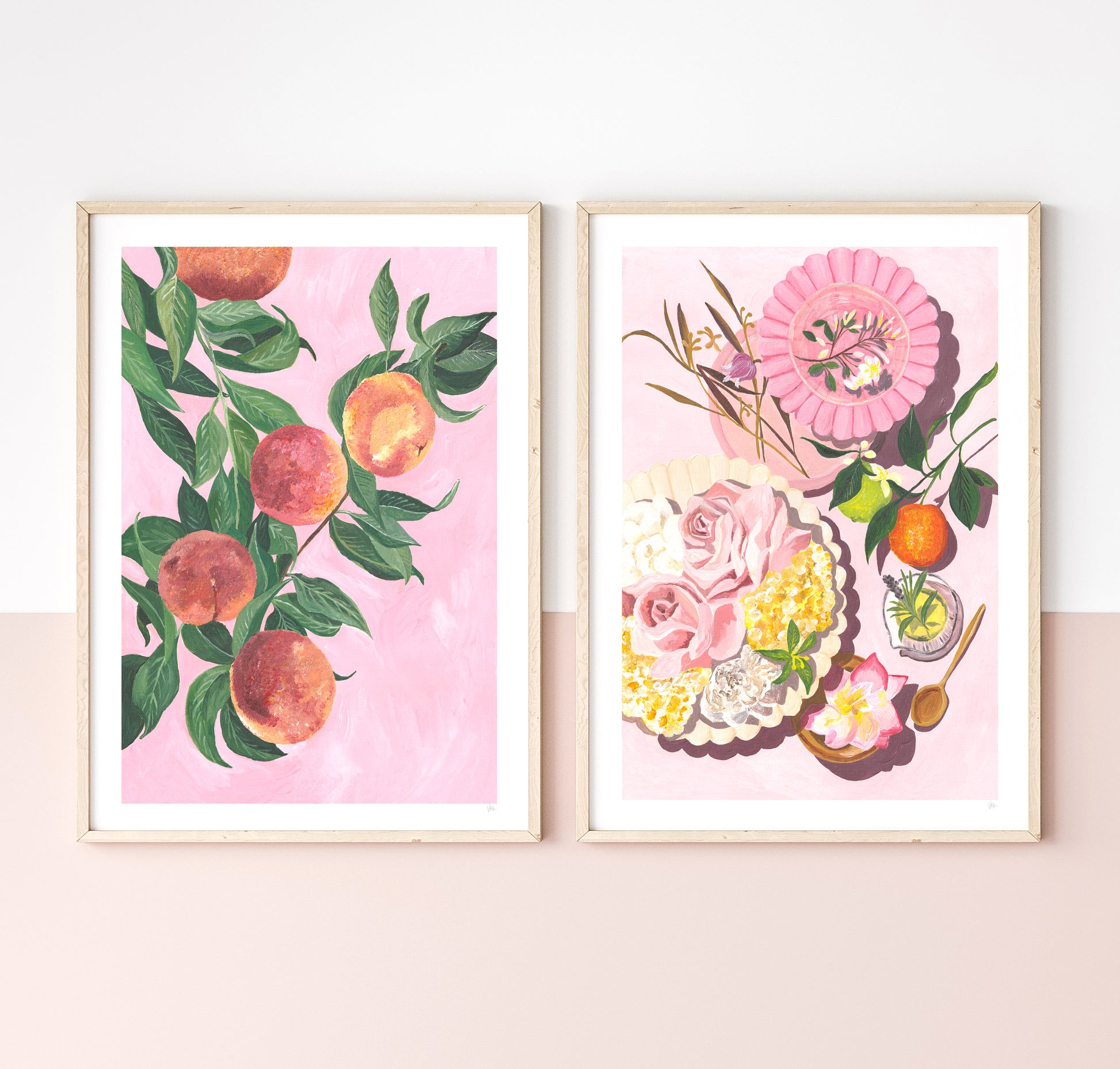 Two framed artworks on a wall, one with peaches and the other with flowers and fruit.