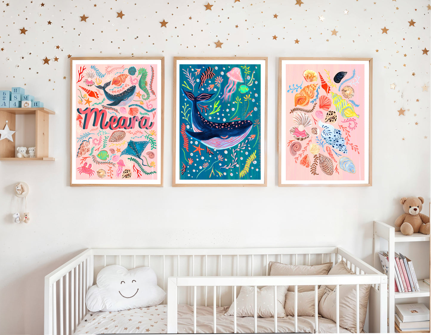 Children's room with framed under the sea themed artworks a name artwork surroud by sea animal illustrations, a blue whale and a collection of different sea shell illustrations and a crib