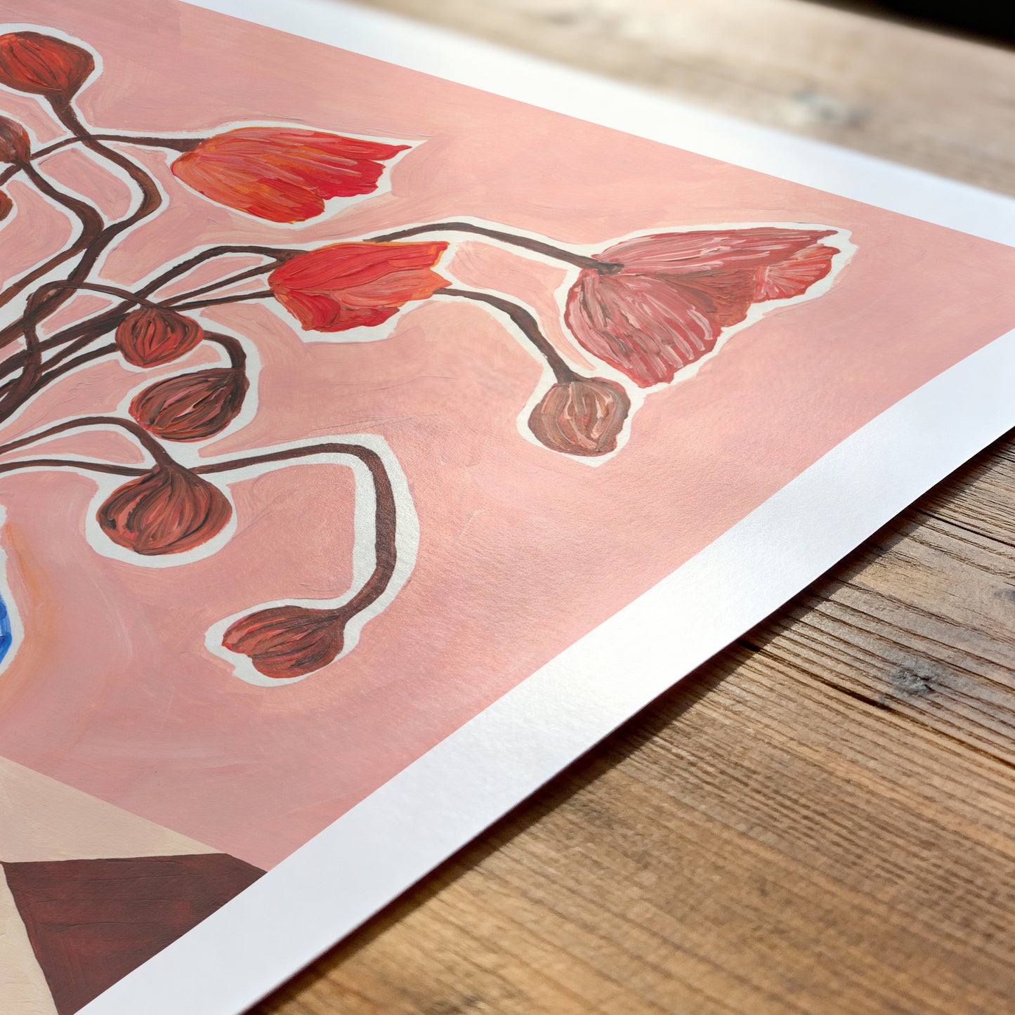 Art print with red floral design on a wooden surface