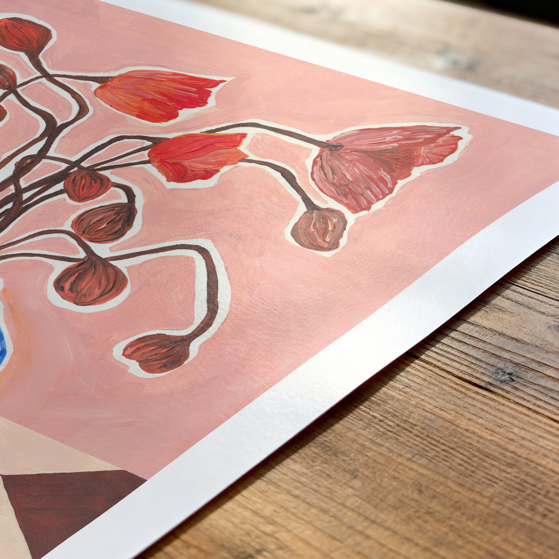 Art print with red floral design on a wooden surface