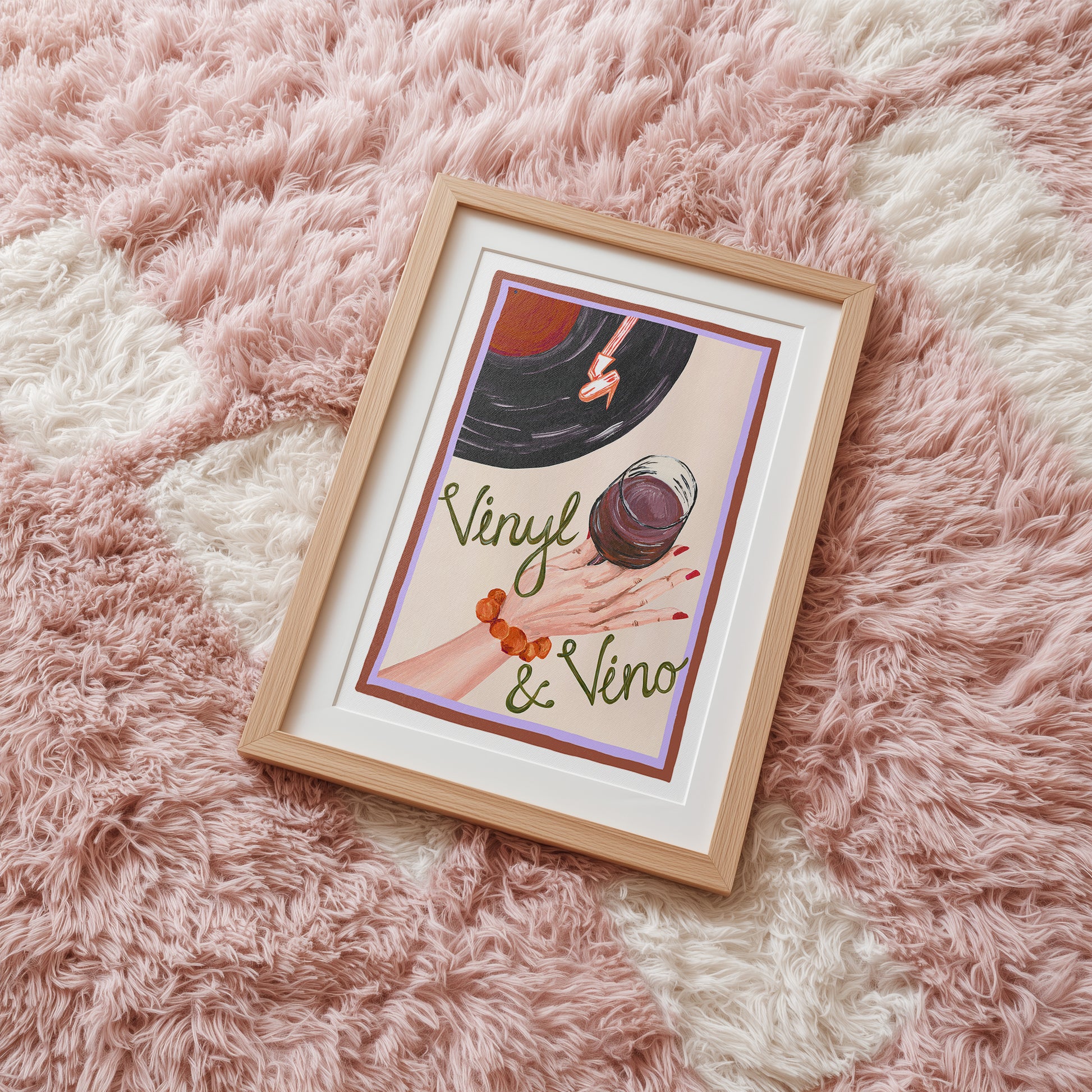 Framed artwork with 'Vinyl & Vino' text on a fluffy pink surface