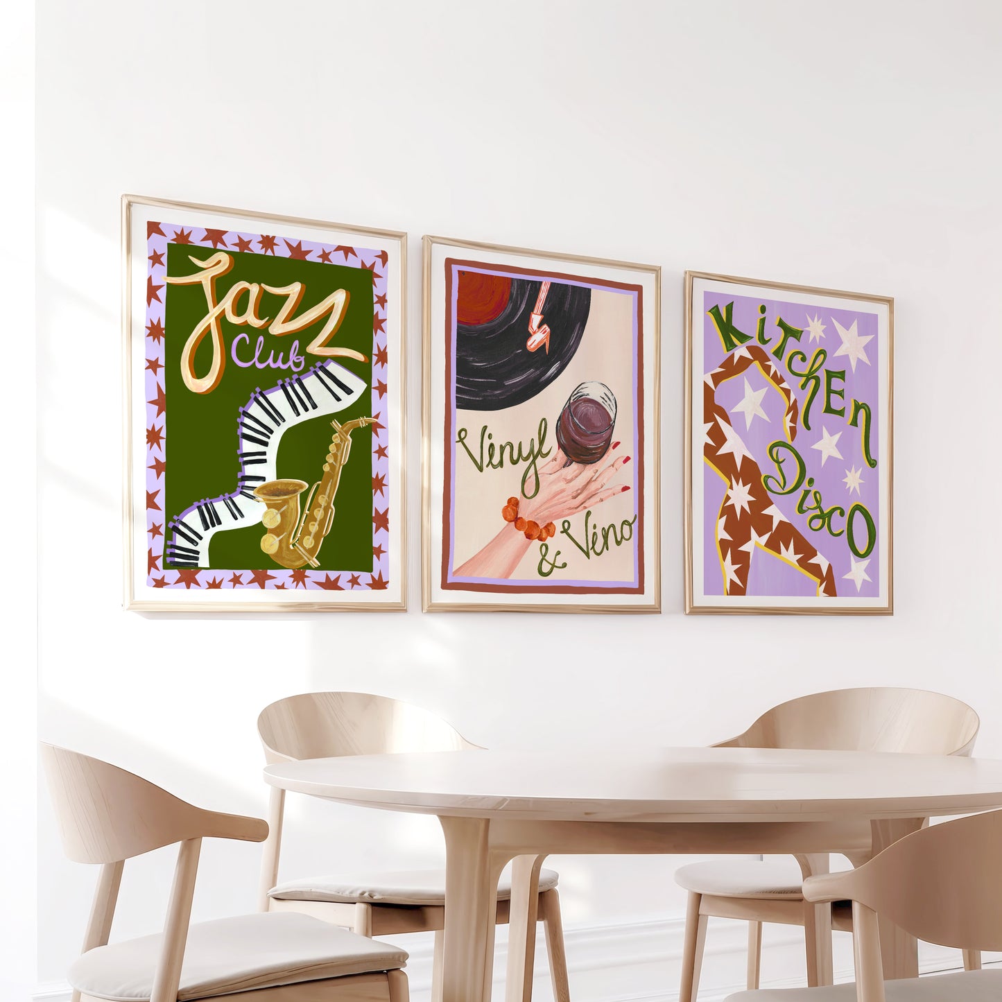 Three colorful framed posters on a wall above a dining table with chairs.