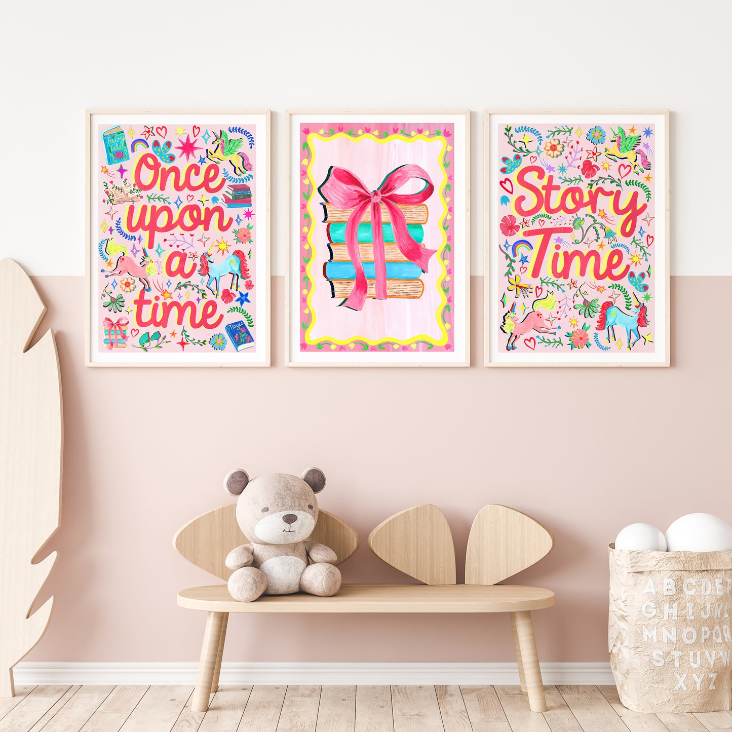 Three colorful children's posters on a wall with a wooden bench and teddy bear below.