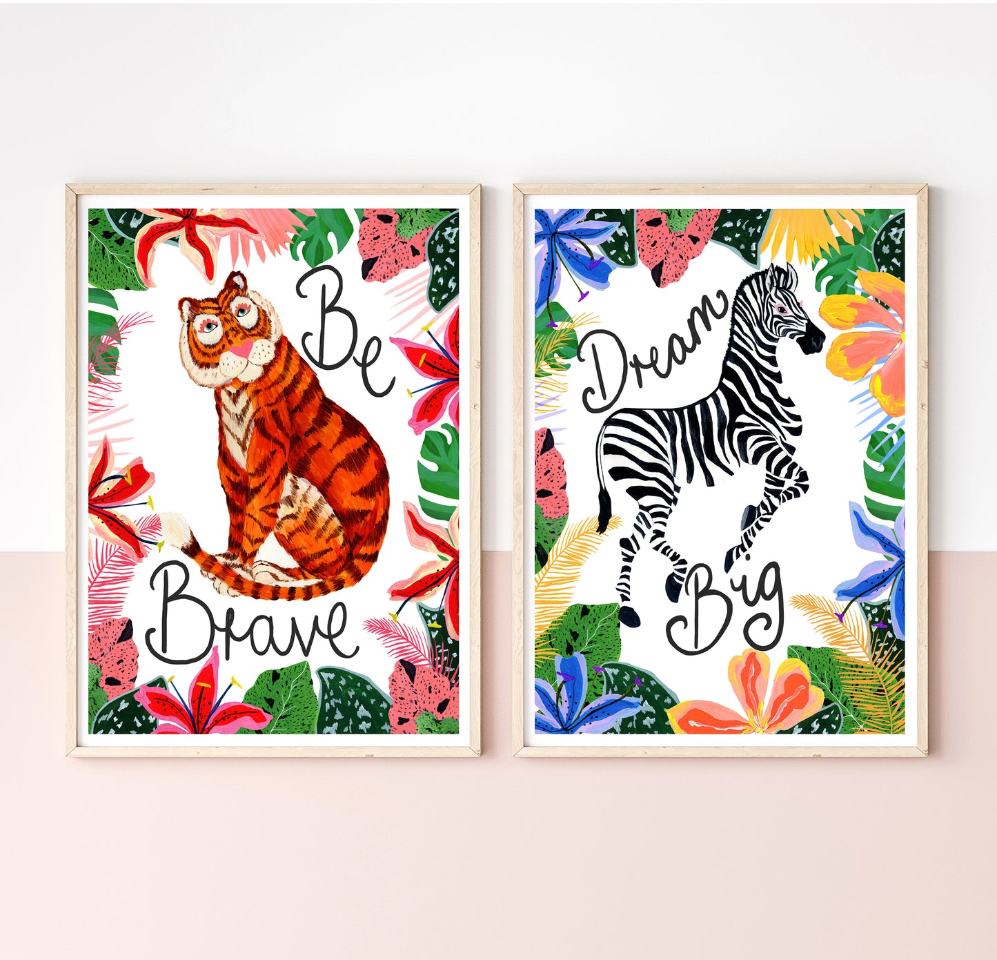 Two framed animal-themed prints with motivational phrases on a white wall.