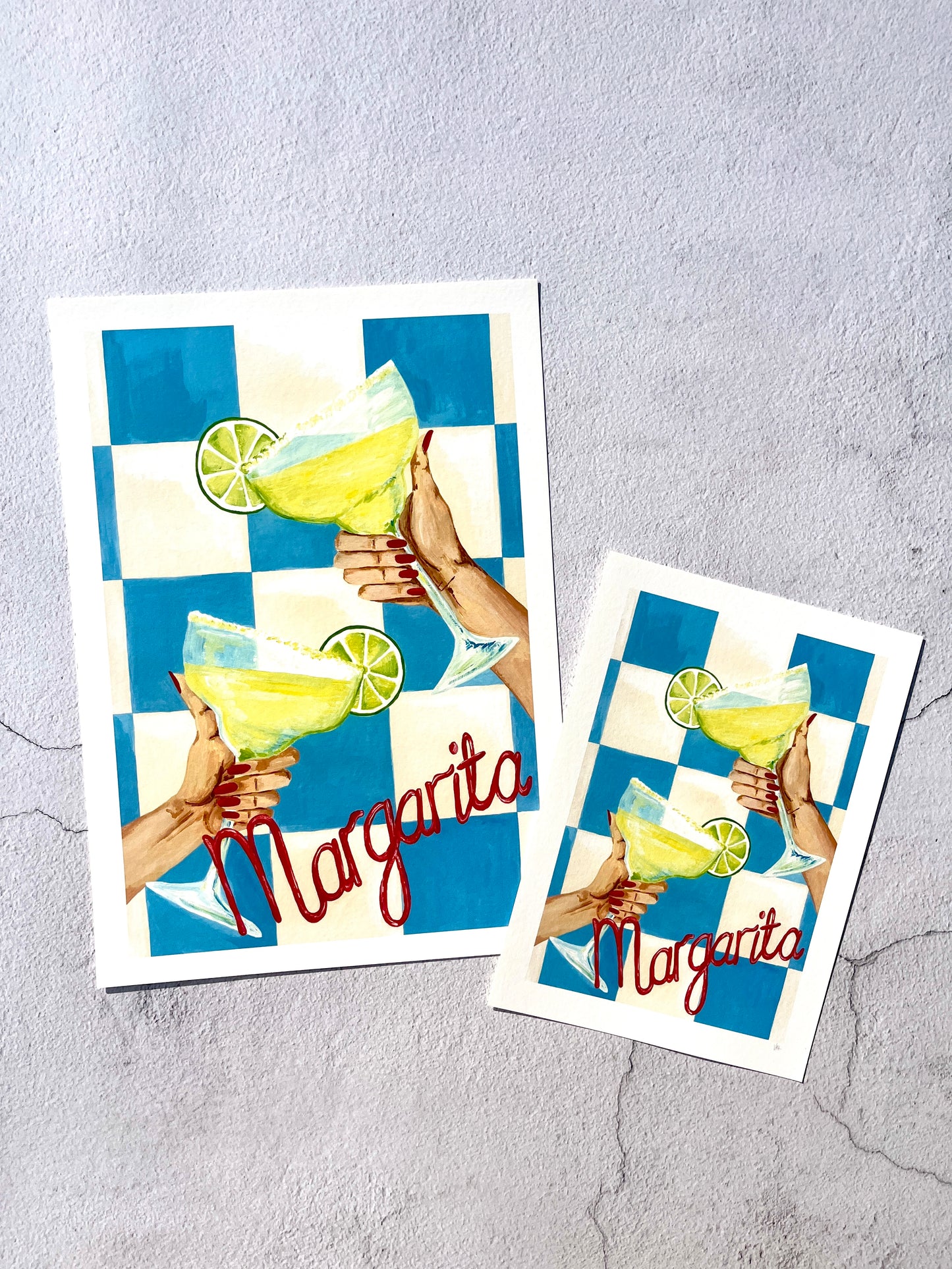Two decorative art prints with a margarita illustration on a textured gray surface.