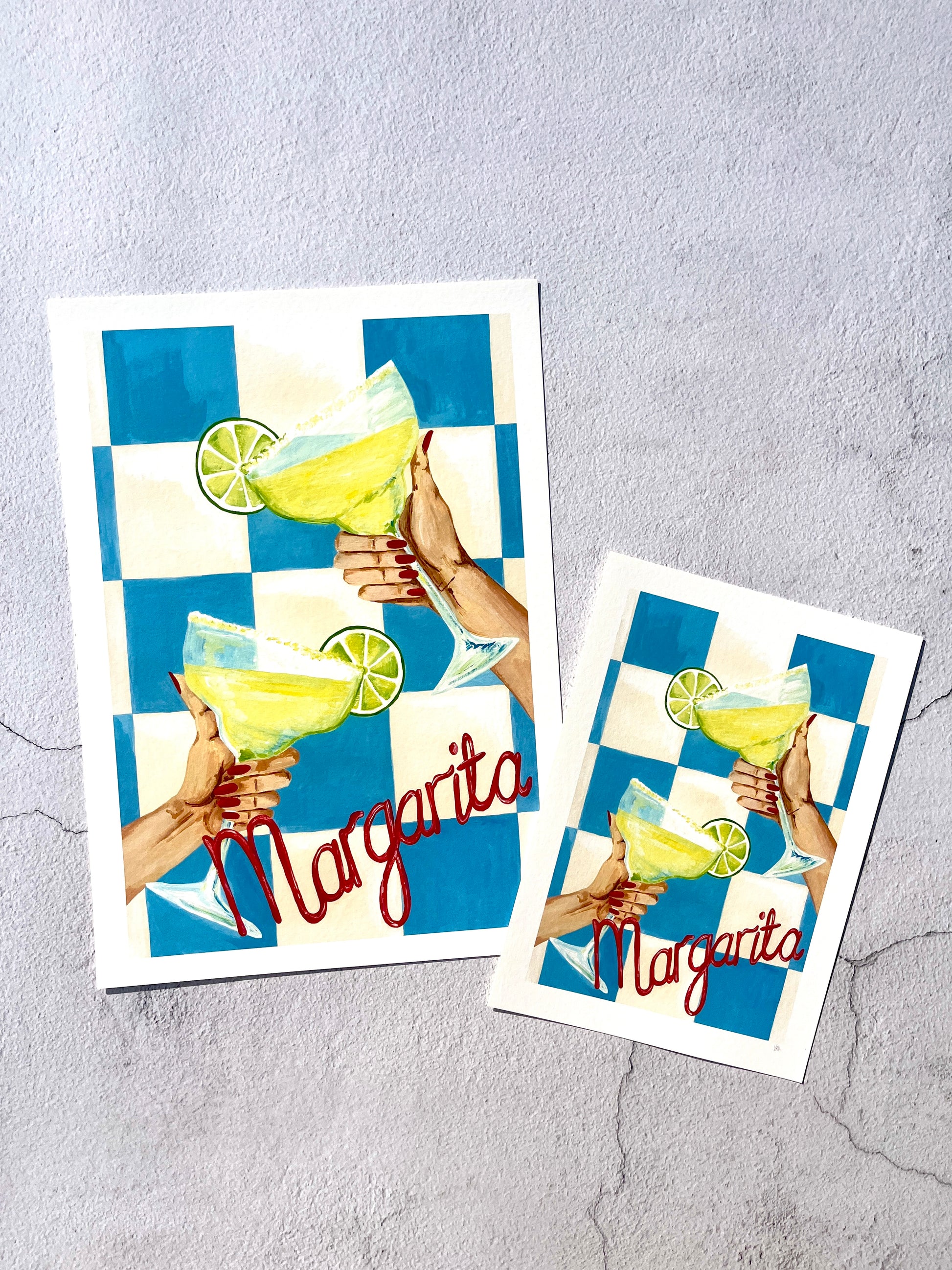 Two decorative art prints with a margarita illustration on a textured gray surface.