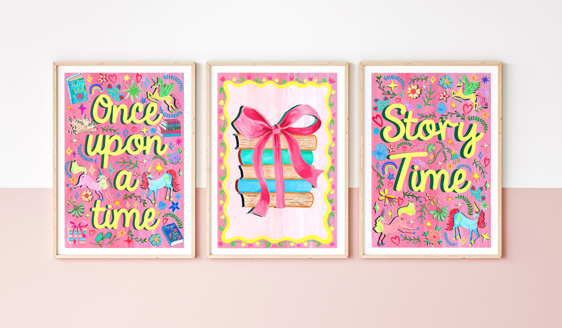 Three colorful framed prints with 'Once upon a time', 'Story Time', and a gift box design on a pink wall.
