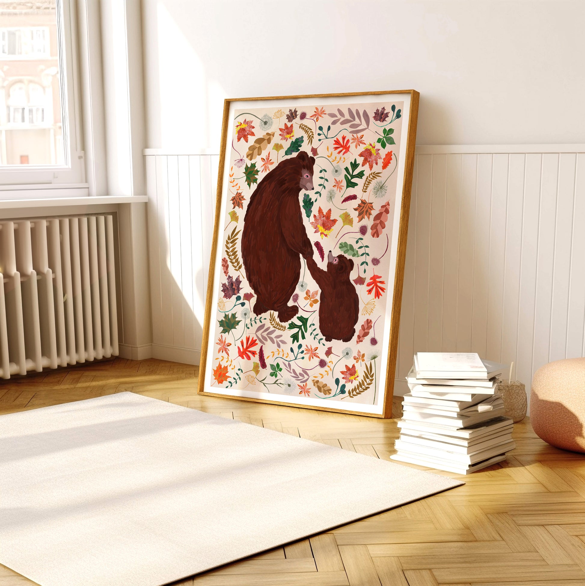 Framed artwork of a bear and cub with autumn leaves in a room with a radiator and books.