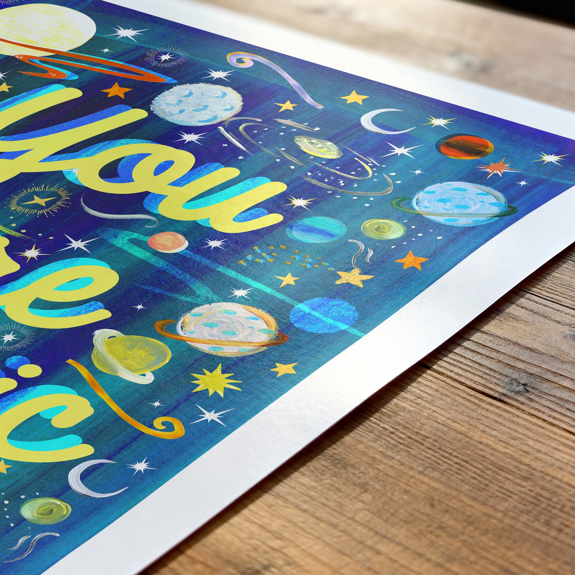 Colorful space-themed poster with planets and stars on a wooden surface