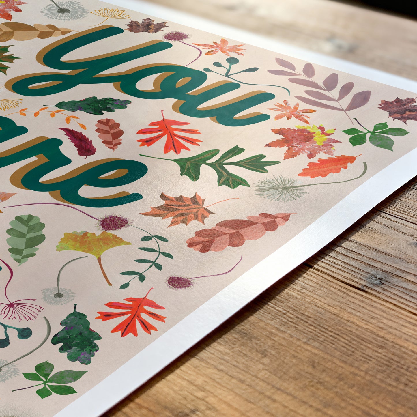 Decorative paper with colorful leaf patterns and the text 'You are' on a wooden surface.