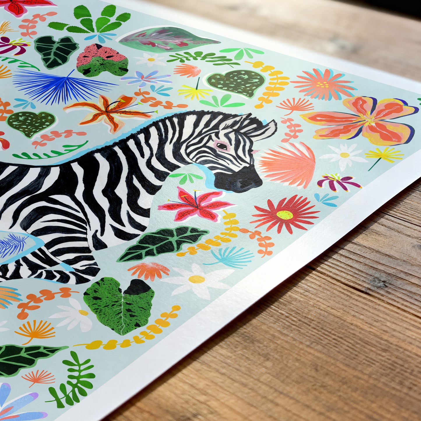Colorful illustration of a zebra surrounded by flowers and leaves on a wooden surface